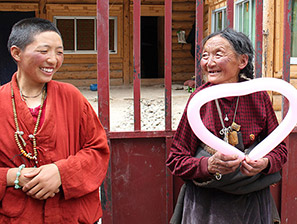 Local Tibetan lady smiling at a heart shaped balloon made for her by a team member
